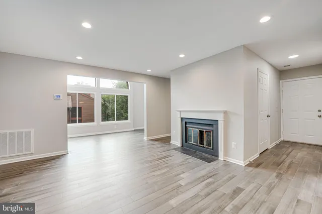 an empty room with wooden floor fireplace and windows