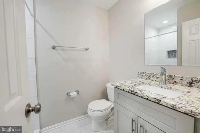 a bathroom with a granite countertop sink toilet and a mirror