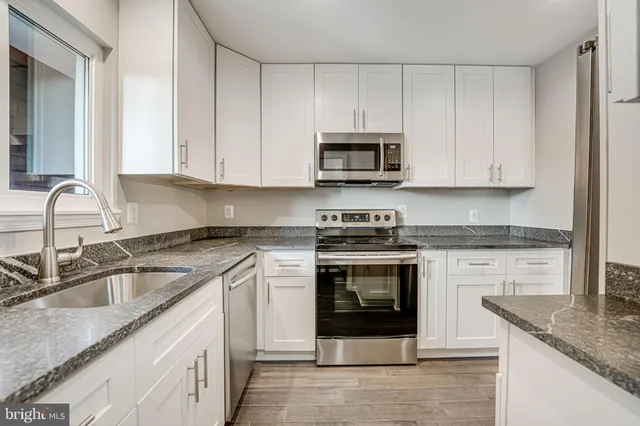 a kitchen with granite countertop white cabinets stainless steel appliances and a sink