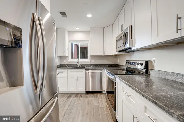 a kitchen with stainless steel appliances granite countertop a refrigerator sink and stove