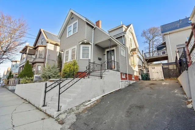 a view of a white house with a yard and potted plants