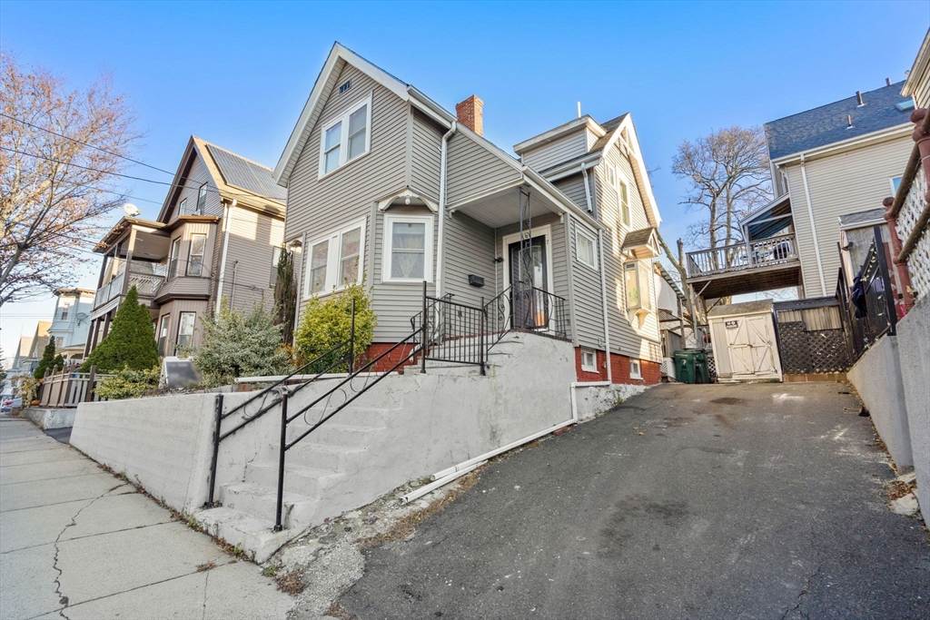 a view of a white house with a yard and potted plants