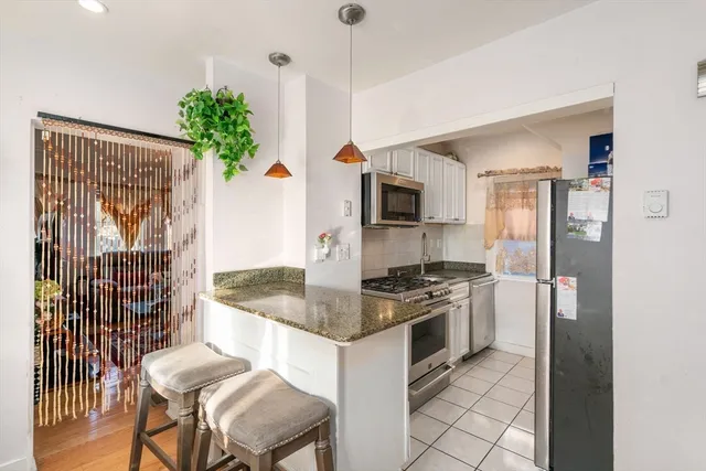 a kitchen with granite countertop kitchen island stainless steel appliances a stove a sink and a refrigerator