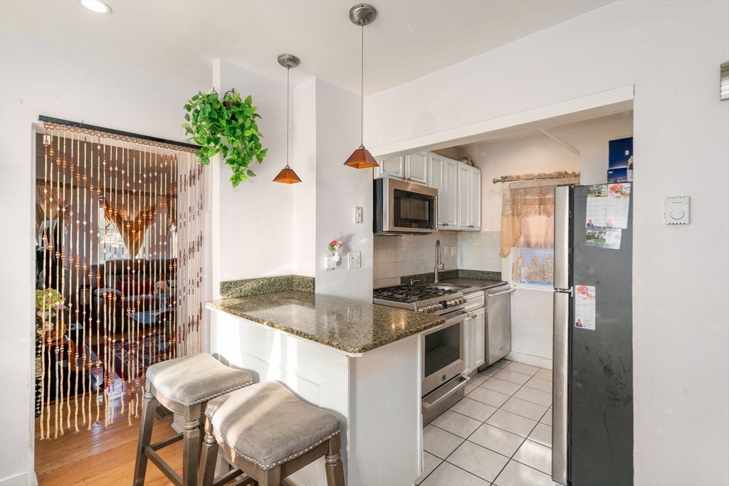 7 Sidney Avenue Lynn, MA 01902 - Photo 5 of 15 a kitchen with granite countertop kitchen island stainless steel appliances a stove a sink and a refrigerator