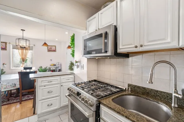 a kitchen with granite countertop a sink a stove and cabinets