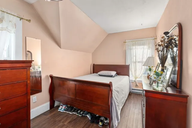 a bedroom with a bed table flowerpot and window