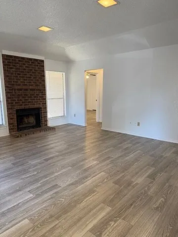 an empty room with wooden floor fireplace and windows