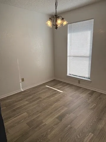 an empty room with wooden floor cabinet and windows