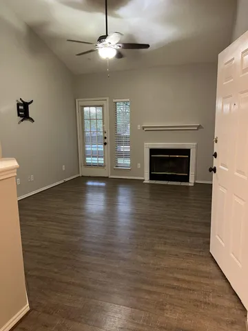 an empty room with wooden floor fireplace and windows