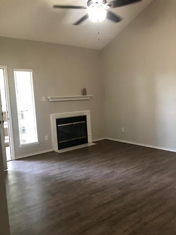 an empty room with wooden floor a fireplace and windows