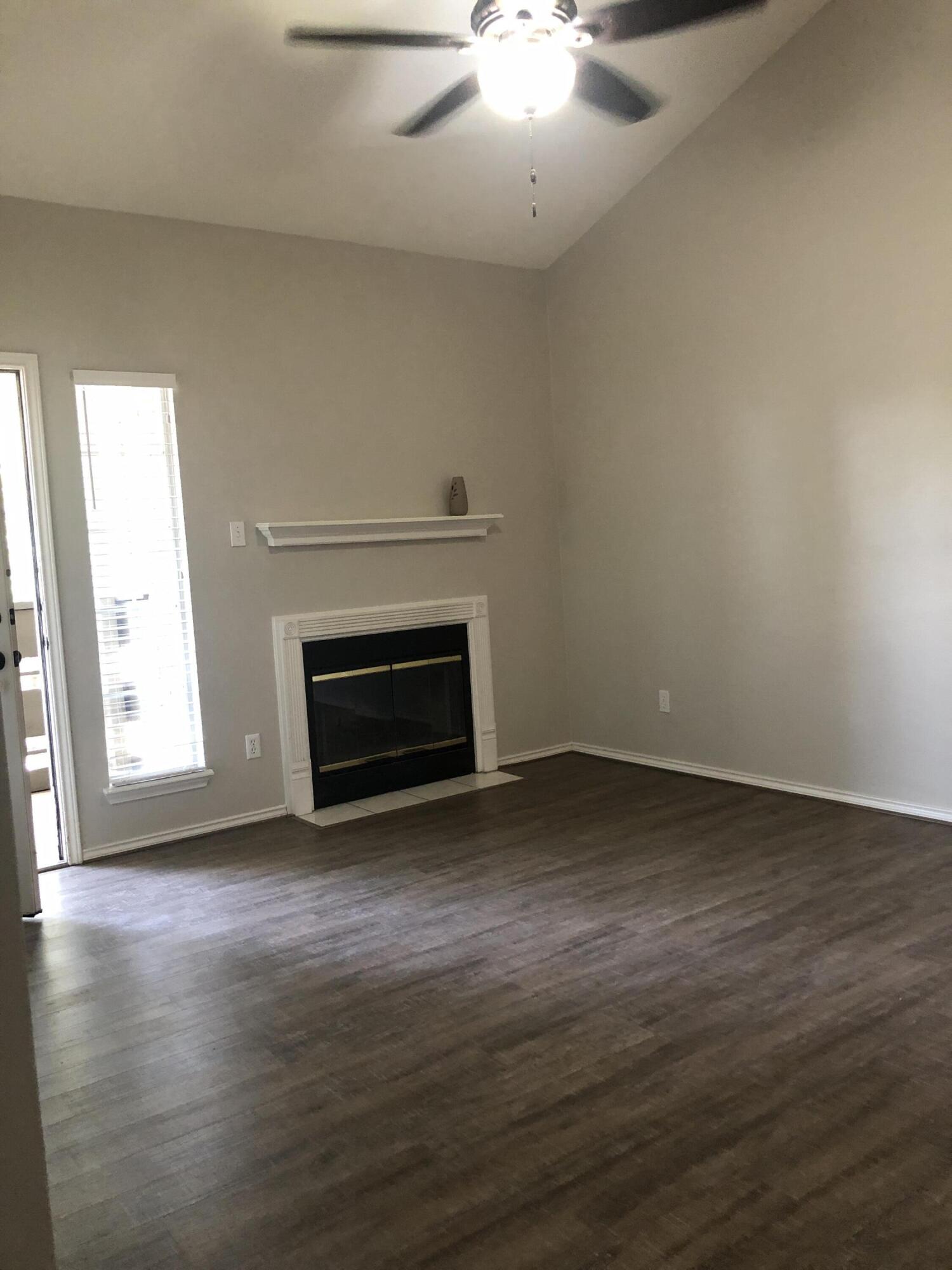 5102 80th Street Lubbock, TX 79424 - Photo 5 of 20 an empty room with wooden floor a fireplace and windows