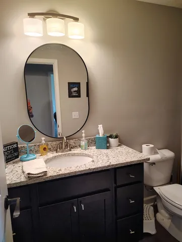 a bathroom with a granite countertop toilet sink and mirror