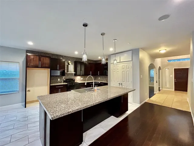 a large kitchen with granite countertop a large counter top stainless steel appliances and cabinets