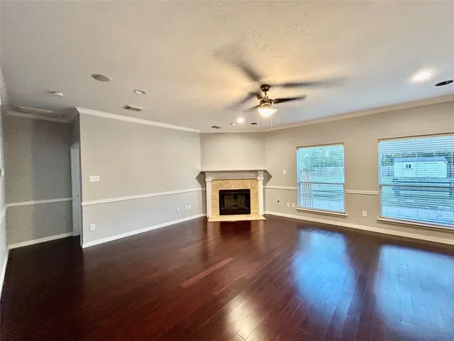 an empty room with wooden floor fireplace and windows