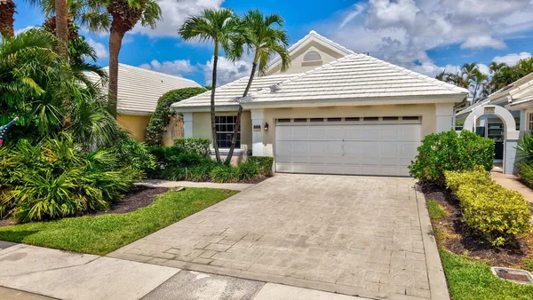a front view of a house with a garden and palm trees