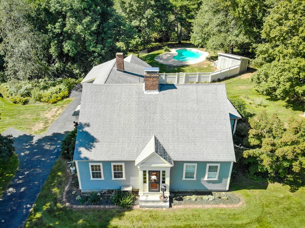 a aerial view of a house with yard and trees in the background