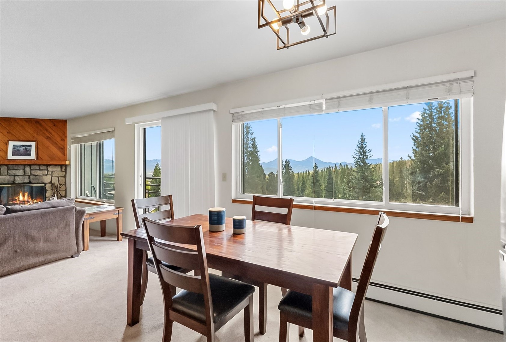 9849 Ryan Gulch Road, Unit 203 Silverthorne, CO 80498 - Photo 12 of 35 Dining area featuring light carpet, a baseboard heating unit, a stone fireplace, and plenty of natural light