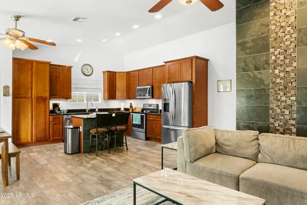 a living room with stainless steel appliances kitchen island granite countertop furniture and a refrigerator