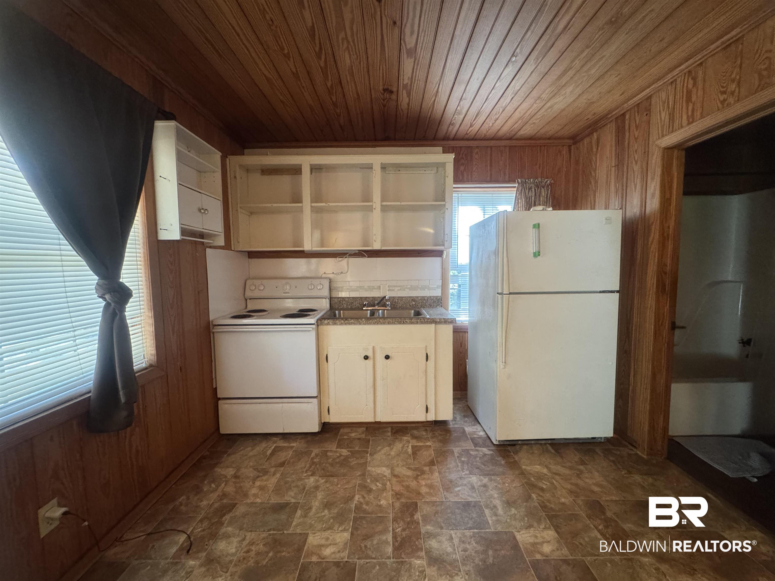3097 Old Castleberry Road Brewton, AL 36426 - Photo 45 of 49 Kitchen with wooden walls, light stone countertops, wood ceiling, and white appliances