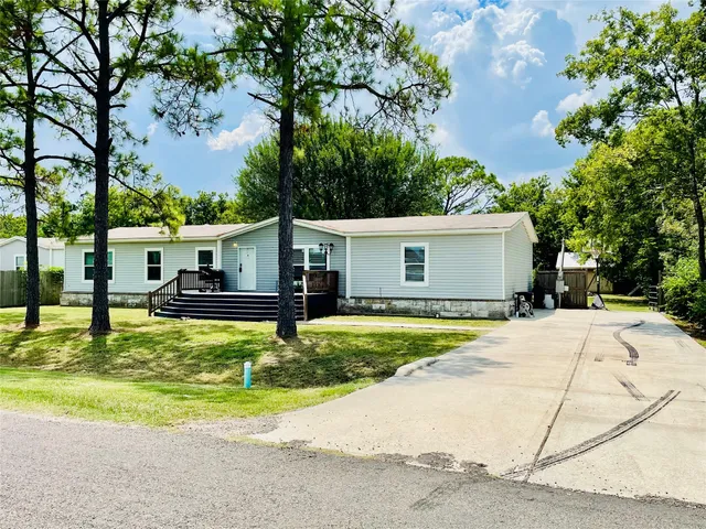 a white house with a large pool lawn chairs and a small yard