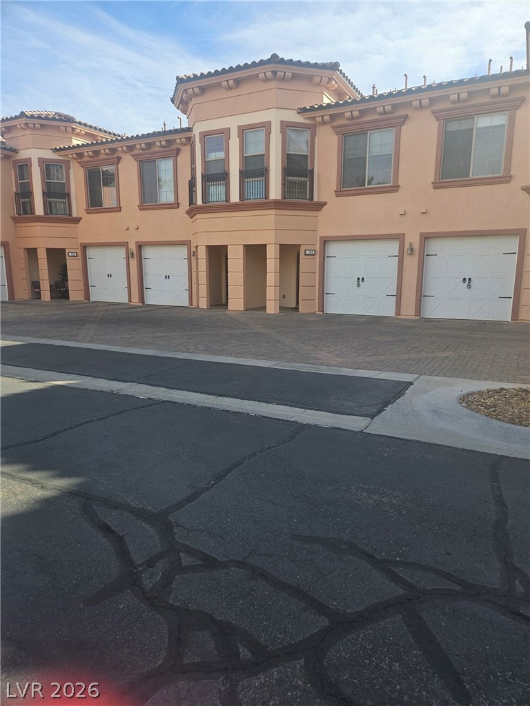 Multi unit property featuring stucco siding, an attached garage, driveway, and a tile roof
