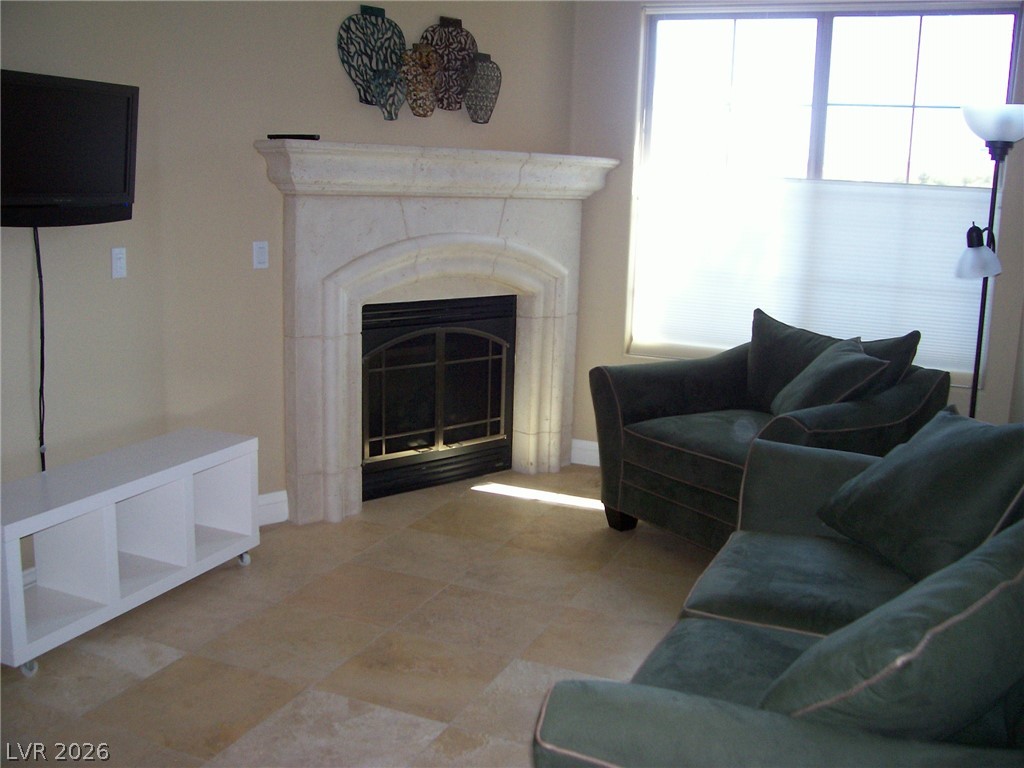 6 Via Vasari, Unit 104 Henderson, NV 89011 - Photo 2 of 13 Living room featuring baseboards and a glass covered fireplace