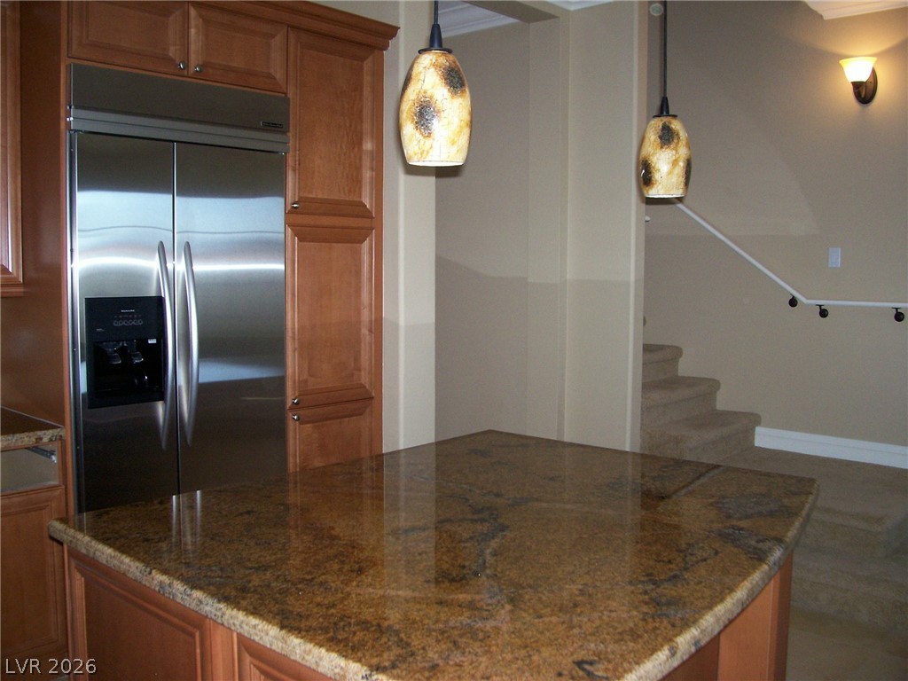 6 Via Vasari, Unit 104 Henderson, NV 89011 - Photo 5 of 13 Kitchen with built in refrigerator, brown cabinets, dark stone countertops, and decorative light fixtures