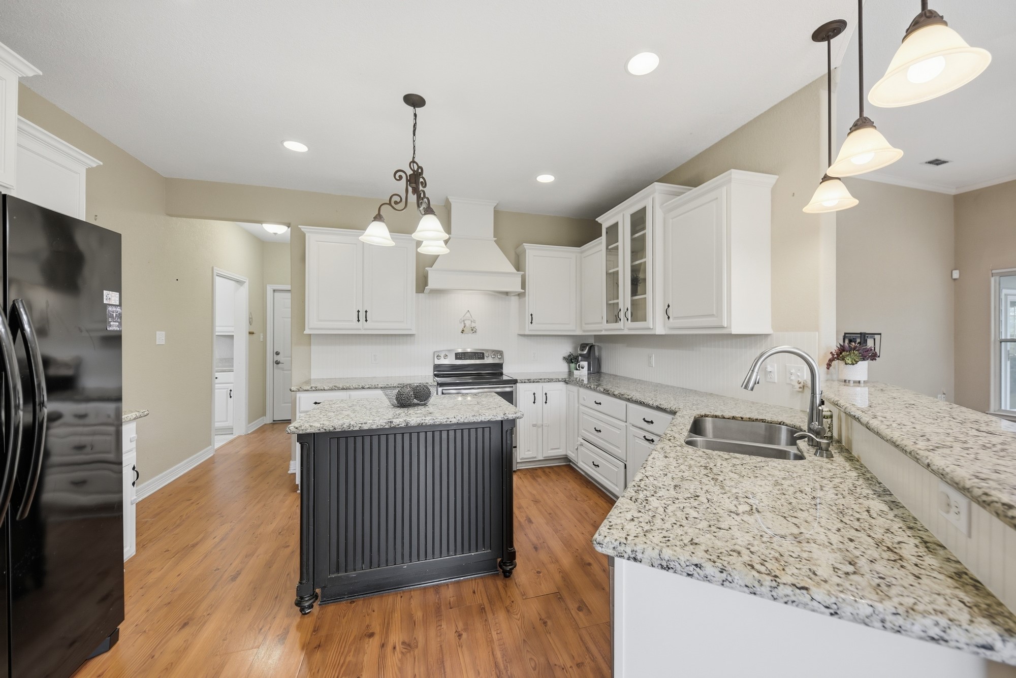 350 Owl Creek Road Giddings, TX 78942 - Photo 8 of 29 Dual tone kitchen with light stone counters, freestanding refrigerator, a peninsula, glass insert cabinets, and dual tone cabinetry
