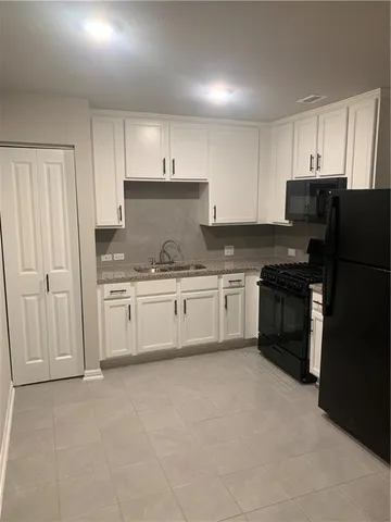 a white kitchen with granite countertop a stove top oven sink and cabinets