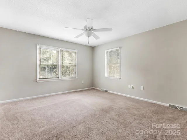 an empty room with windows and ceiling fan
