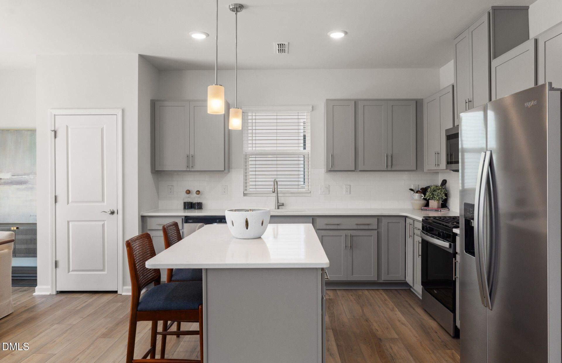 603 Timber Terrace Drive Durham, NC 27704 - Photo 3 of 17 a kitchen with a sink a refrigerator a stove and chairs with wooden floor
