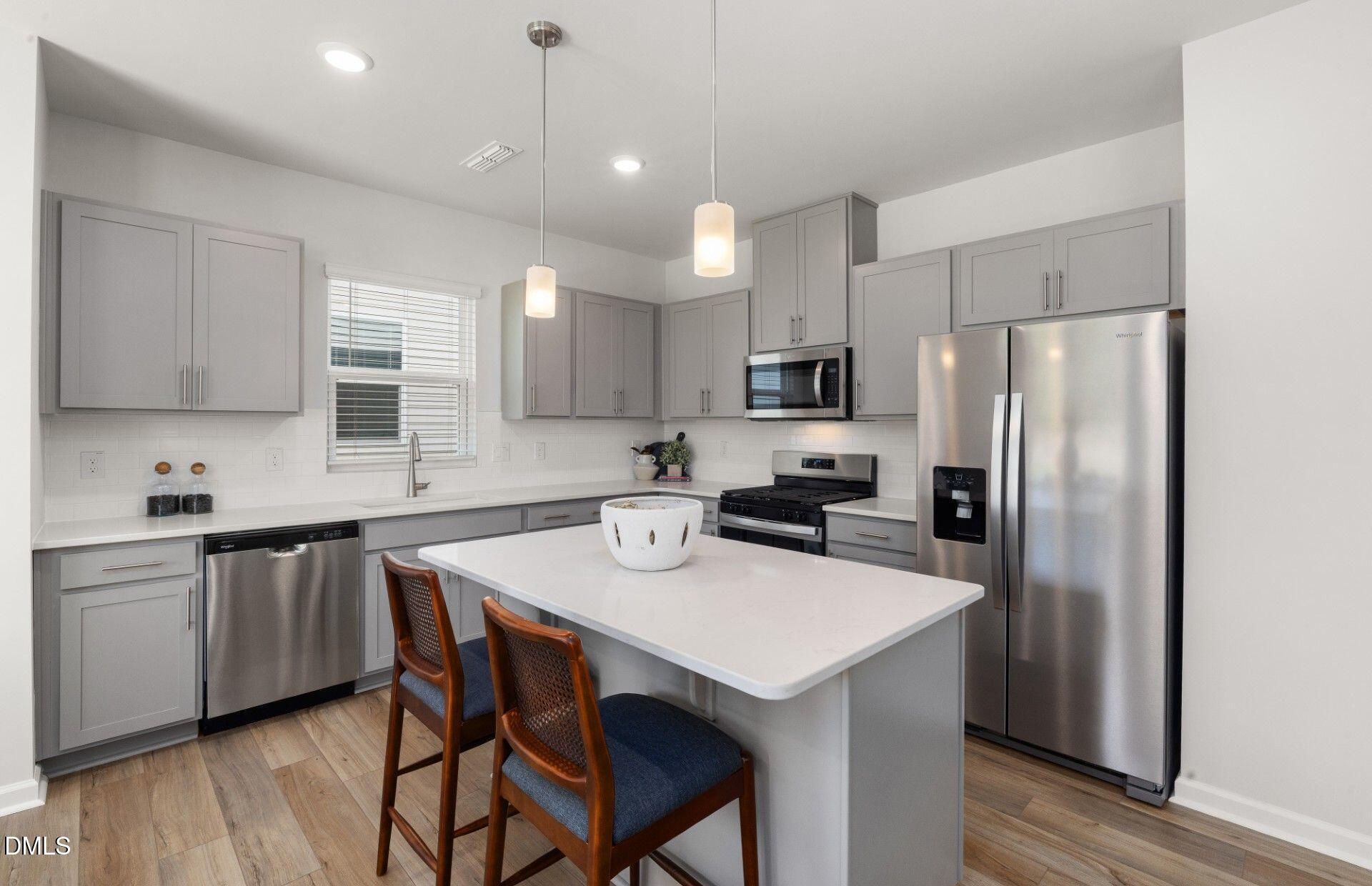 603 Timber Terrace Drive Durham, NC 27704 - Photo 5 of 17 a kitchen with a sink a microwave a refrigerator and white cabinets