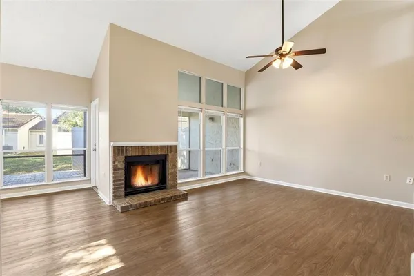 a view of an empty room with wooden floor fireplace and a window