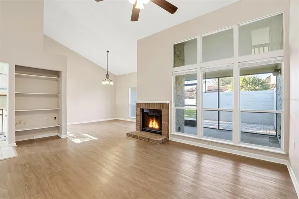 an empty room with wooden floor fireplace and windows