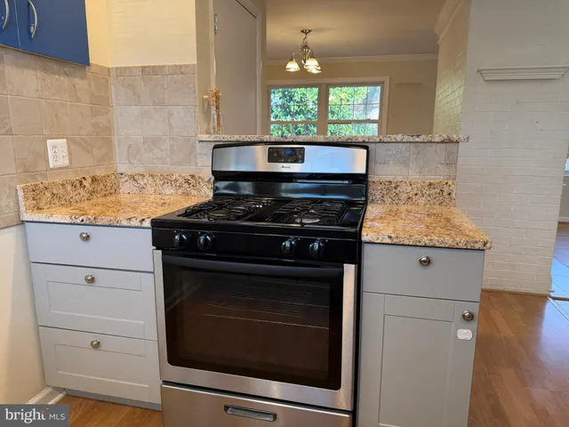 a kitchen with granite countertop a stove microwave and cabinets