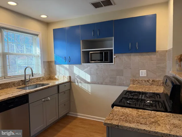 a kitchen with sink a microwave a stove and cabinets