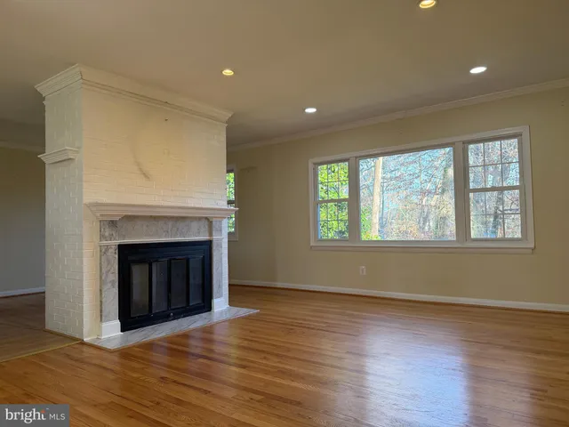 an empty room with wooden floor fireplace and windows