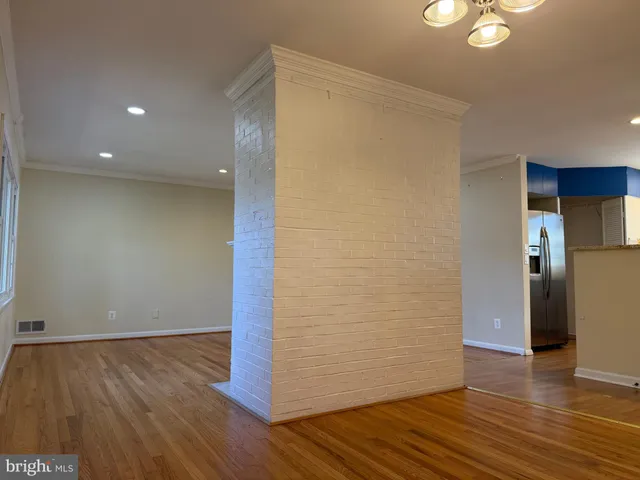 a view of an empty room with wooden floor and closet
