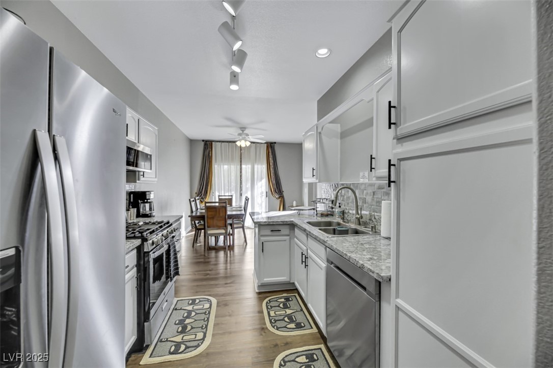 2907 Rio Sonora Court Henderson, NV 89074 - Photo 14 of 35 Kitchen with appliances with stainless steel finishes, dark wood-style floors, decorative backsplash, white cabinets, and recessed lighting