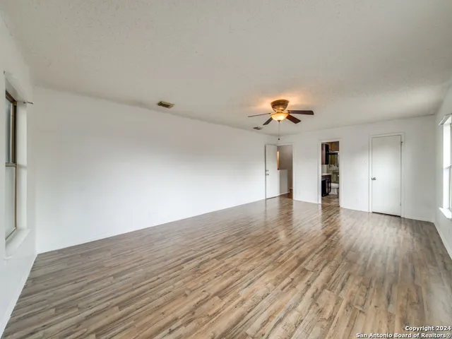a view of an empty room with window and wooden floor