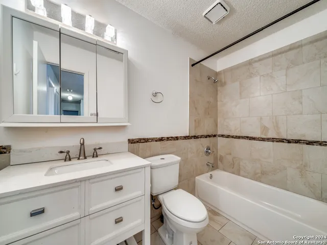 an empty room with chandelier fan and windows