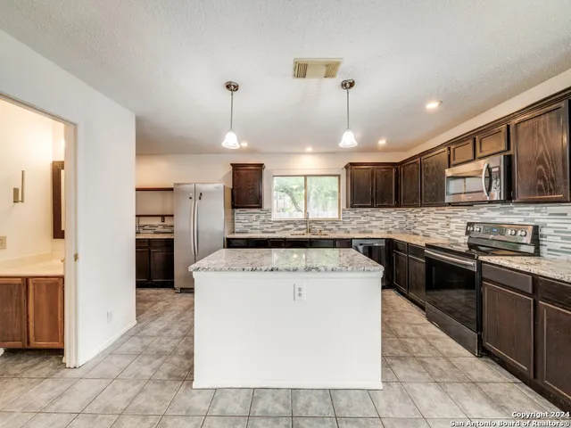 a kitchen with stainless steel appliances granite countertop a stove a sink and a refrigerator