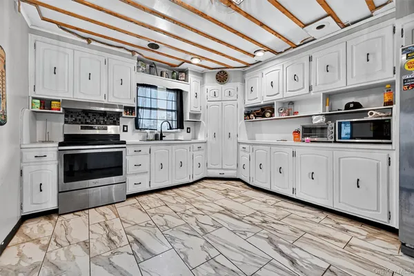 a kitchen with stainless steel appliances granite countertop a sink a stove a refrigerator and white cabinets