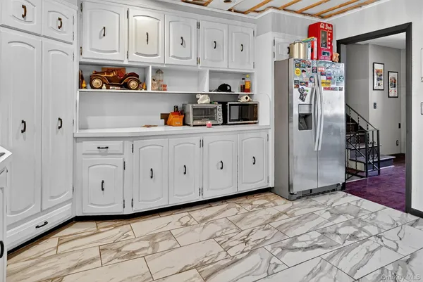 a kitchen with white cabinets and wooden floor