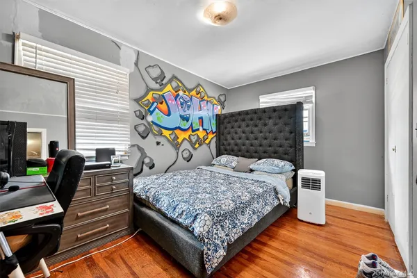 a bedroom with a bed and dresser with wooden floor