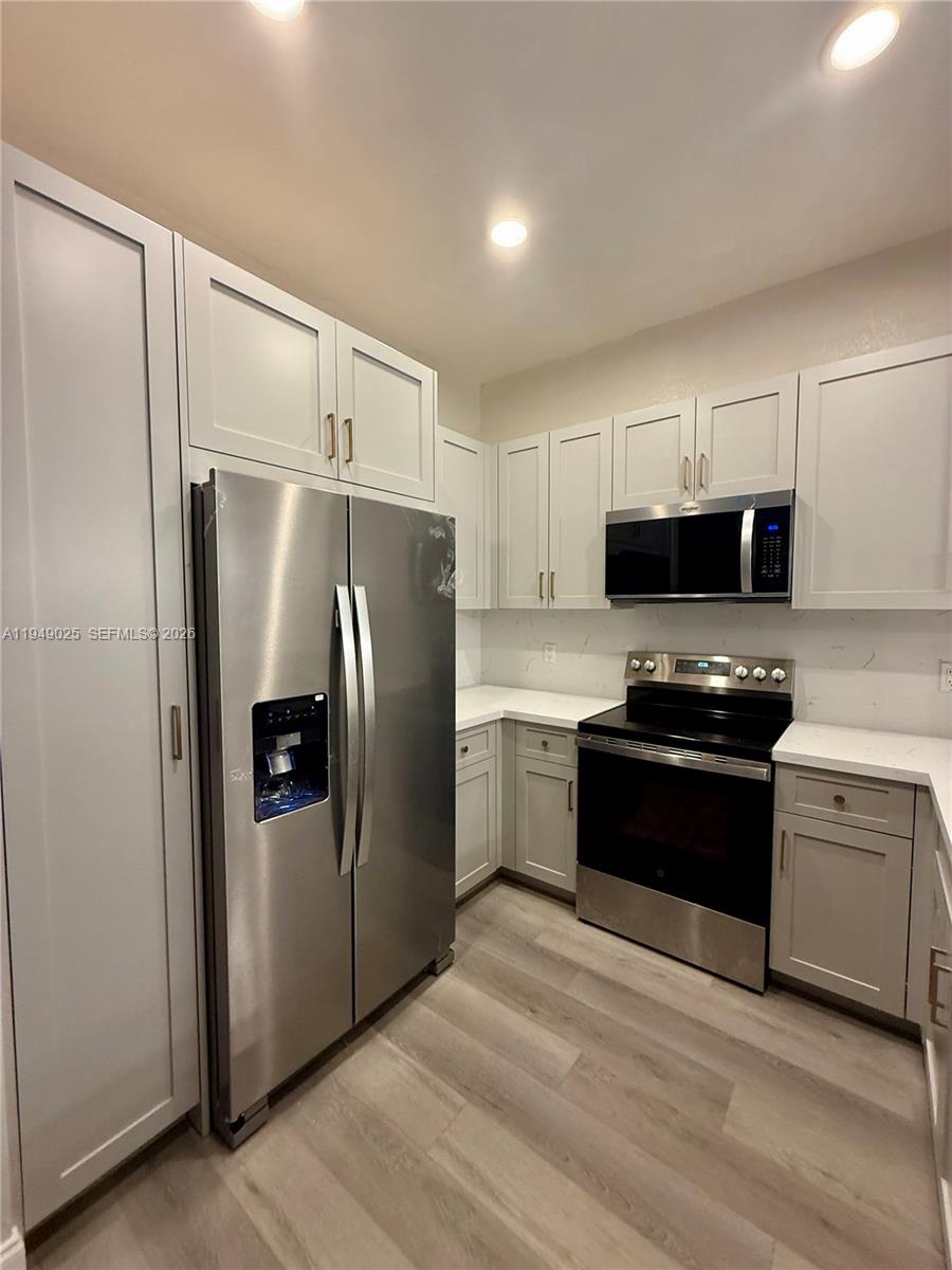 2511 Southwest 99th Way, Unit 2511 Miramar, FL 33025 - Photo 3 of 23 a kitchen with granite countertop a refrigerator stove and microwave