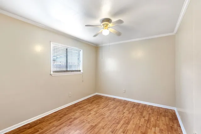 a view of an empty room with wooden floor and a fan