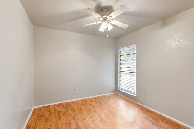 an empty room with a chandelier fan and windows