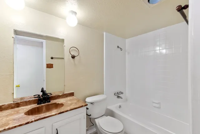 a bathroom with a granite countertop sink toilet and shower