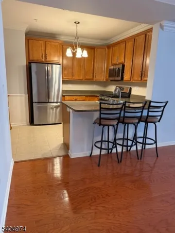 a kitchen with stainless steel appliances granite countertop a refrigerator a stove a kitchen island a dining table and chairs with wooden floor